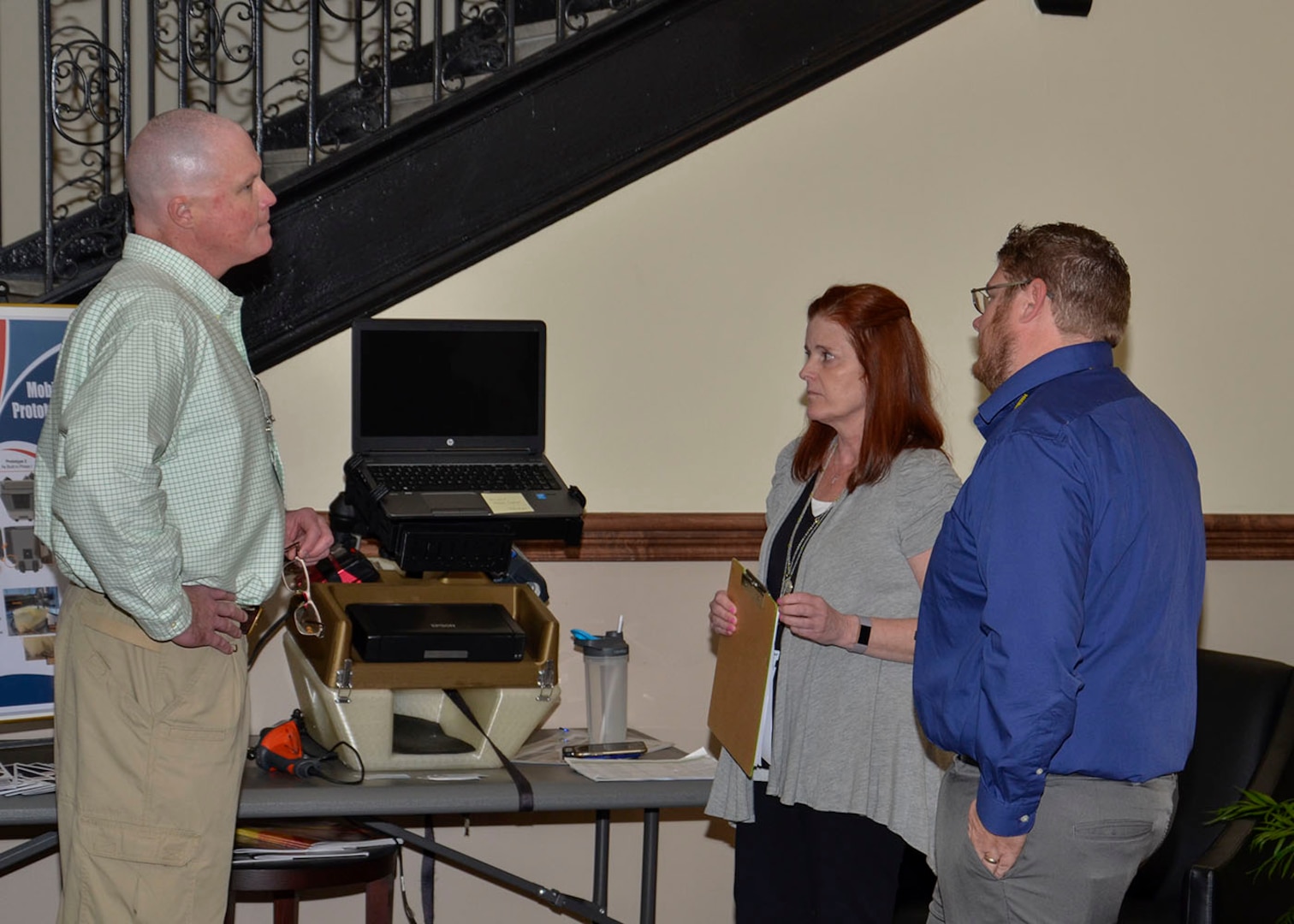 Kristy McNally (center) discusses the mobile work station's features with two summit attendees.