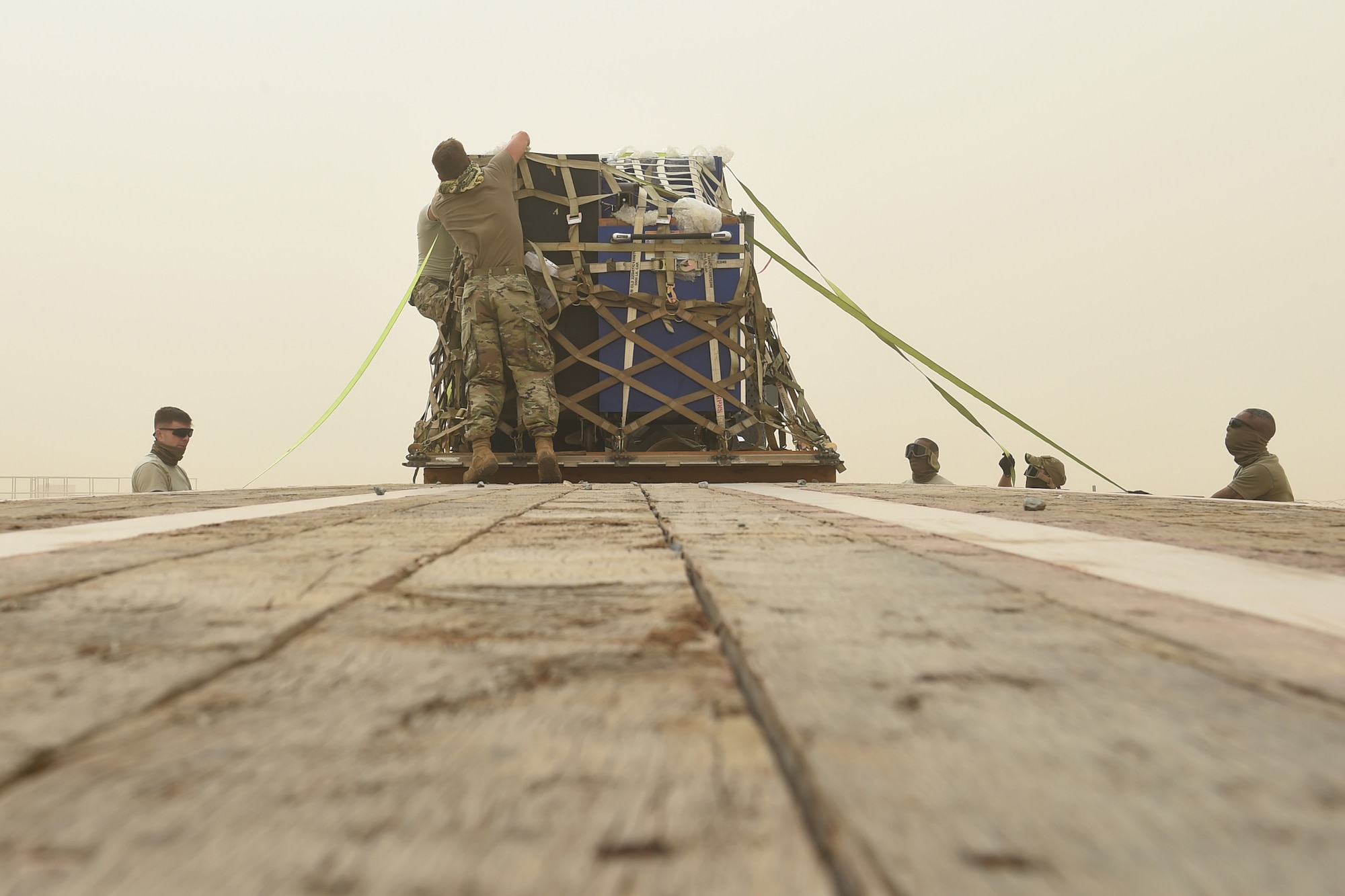 Airmen put a pallet on a flat bed truck