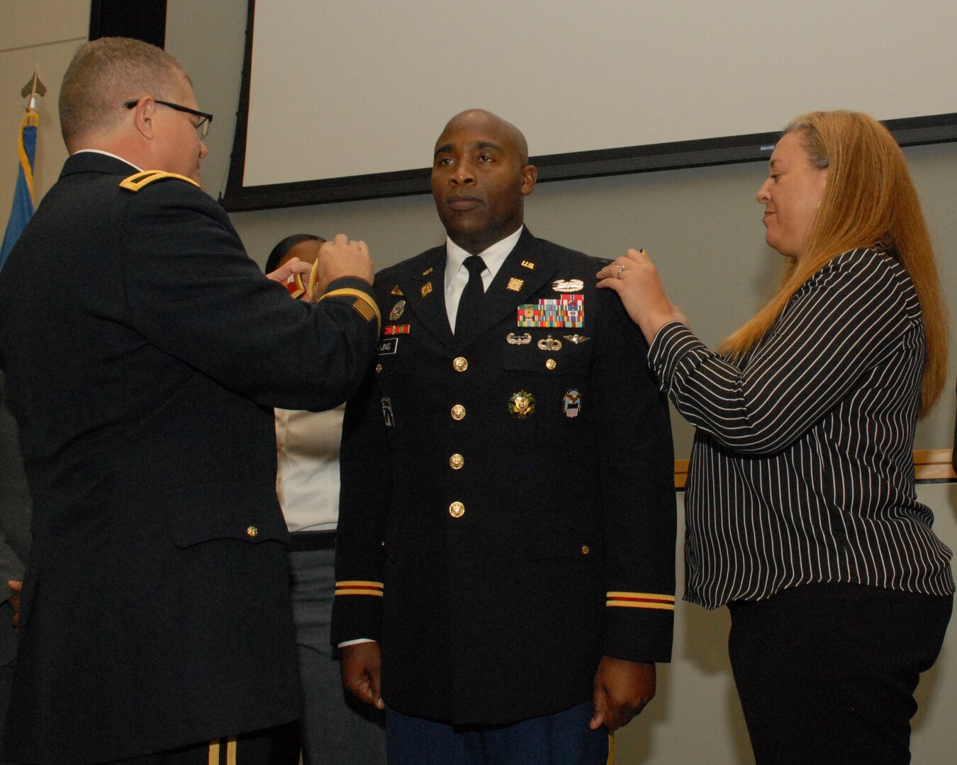 Army Brig. Gen. Mark Simerly, DLA Troop Support commander, (left) and Dr. Kim Young, wife, (right) place the new colonel rank on the shoulders of Col. Abel Young during his promotion ceremony at DLA Troop Support in Philadelphia, Oct. 25, 2018. Young, a Chicago Heights, Ill., native, is the director of the Subsistence supply chain. (Photo by Ed Maldonado/DLA Troop Support)