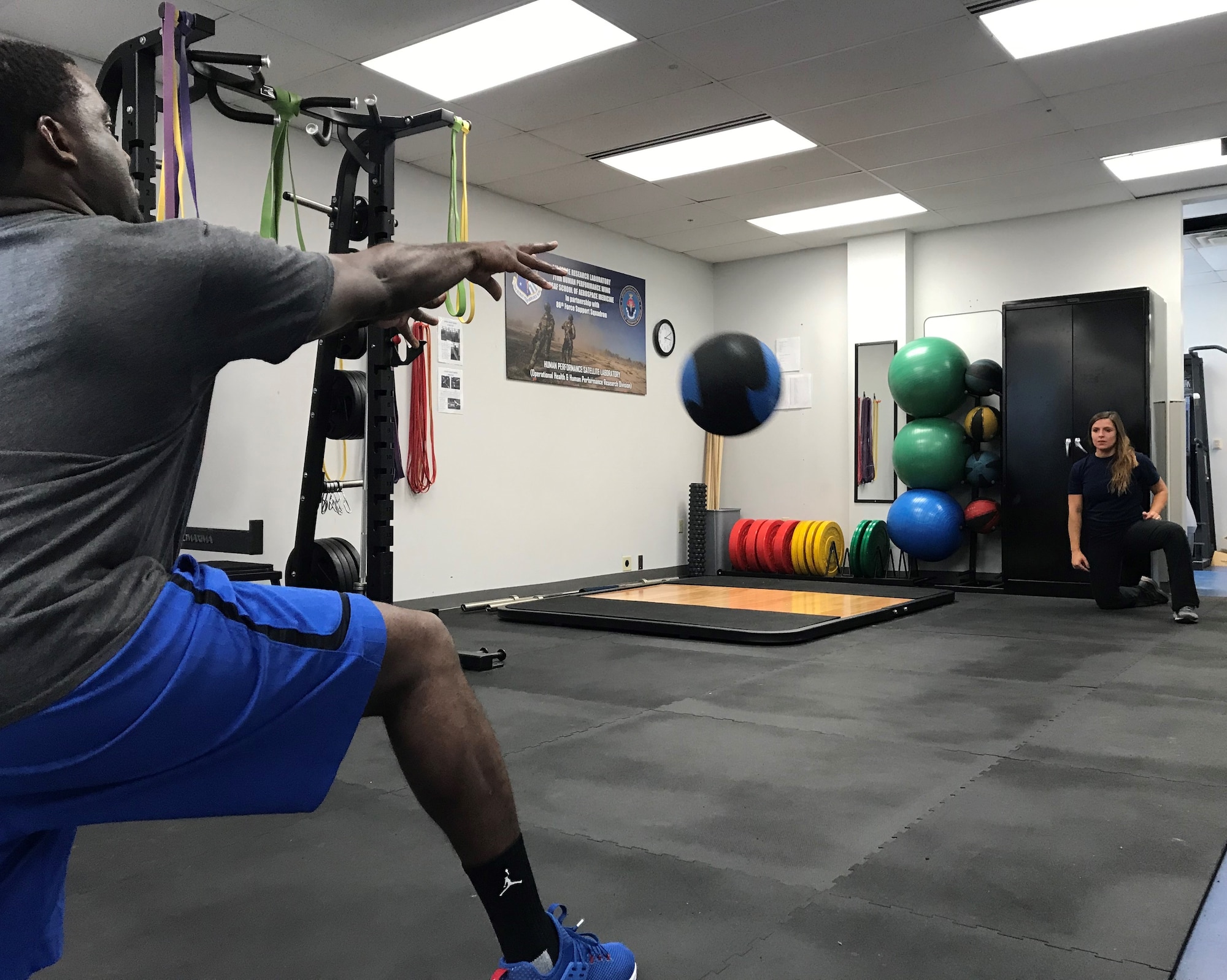 Master Sgt. Markus Manuel, USAFSAM NCOIC Officer and Management Branch (left), tosses a weighted ball during his training session with Ashley Kessler United States Air Force School of Aerospace Medicine research athletic trainer. (U.S. Air Force photo/Stacey Geiger)
