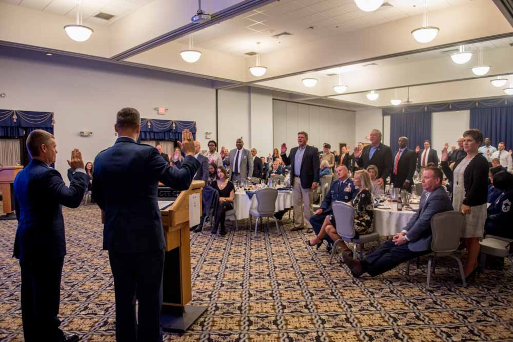 Cols. Craig Peters, 512th Airlift Wing commander, left, and Joel Safranek, 436th Airlift Wing commander, right, administers the oath during the Honorary Commander Induction ceremony at Dover Air Force Base, Delaware, Oct. 20, 2018. Peters, and Safranek administered the oath to 23 new Honorary Commander inductees. (U.S. Air Force photo by Staff Sgt. Damien Taylor)