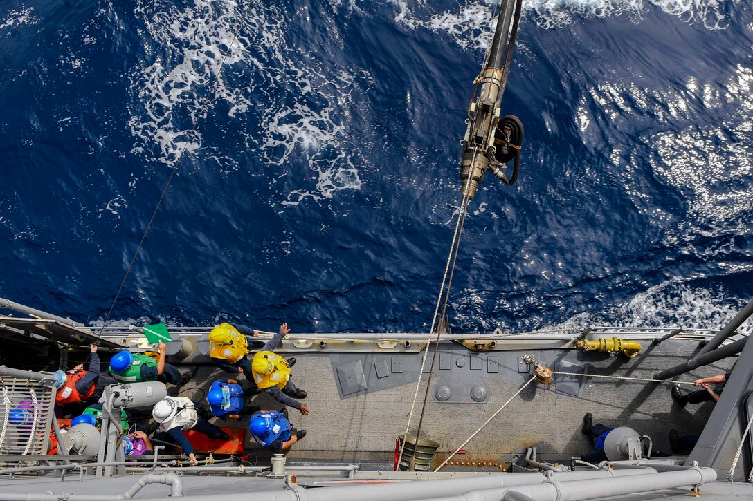 Sailors prepare  to receive a fuel line.