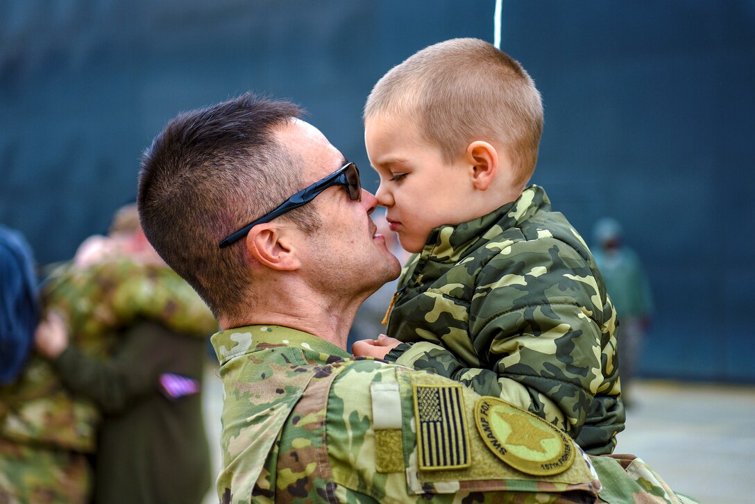 An airman hugs a child.