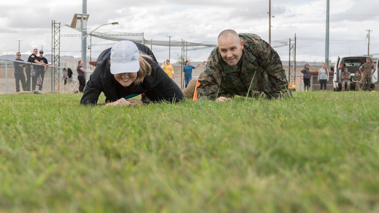 Col. Craig Clemans, Base Commander, low crawls with his wife, Ruth, during the Combat Fitness Test portion of Jane Wayne Day aboard Marine Corps Logistics Base Barstow, Calif., Oct. 12.
(U.S. Marine Corps Photo by Jack J. Adamyk)