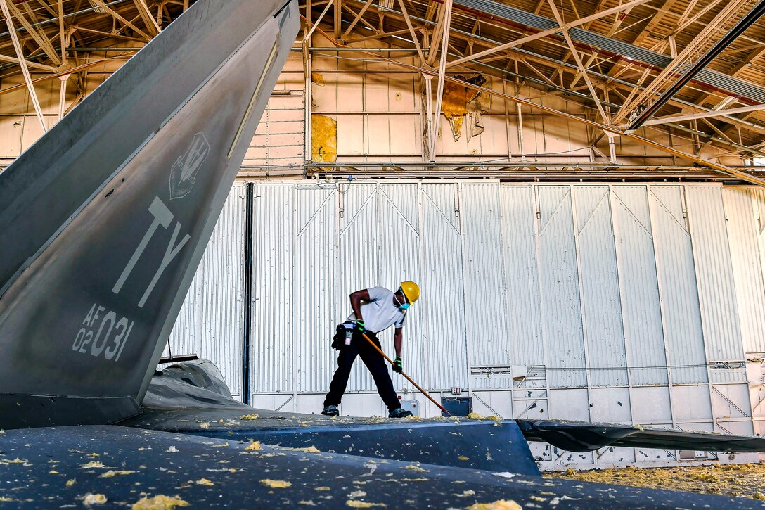 An airman sweeps debris off an aircraft.