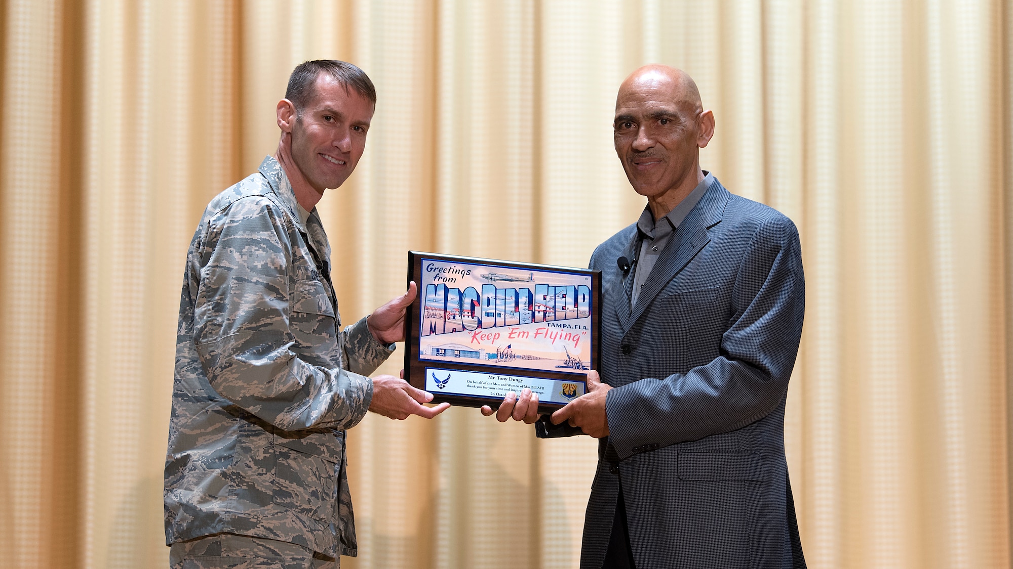 U.S. Air Force Col. Stephen Snelson, the 6th Air Mobility Wing commander, presents former National football League head coach, Tony Dungy, a plaque in appreciation for speaking at MacDill Air Force Base, Fla., Oct 24, 2018. The Super Bowl winning head coach and Pro Football Hall of Fame inductee spoke on moments throughout his life that tested his resiliency.