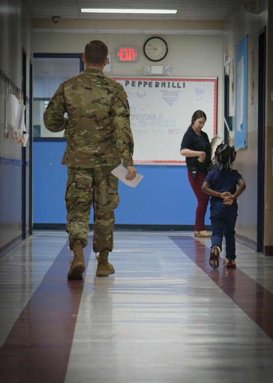 Senior Airman Luke Hamilton, 628th Comptroller Squadron comptroller, walks alongside a student in the hall of Pepperhill Elementary School Oct. 24, 2018, in North Charleston, S.C. Airmen from the 628th CPTS went to the school to read to children and answer any questions the children had about being an Airmen.