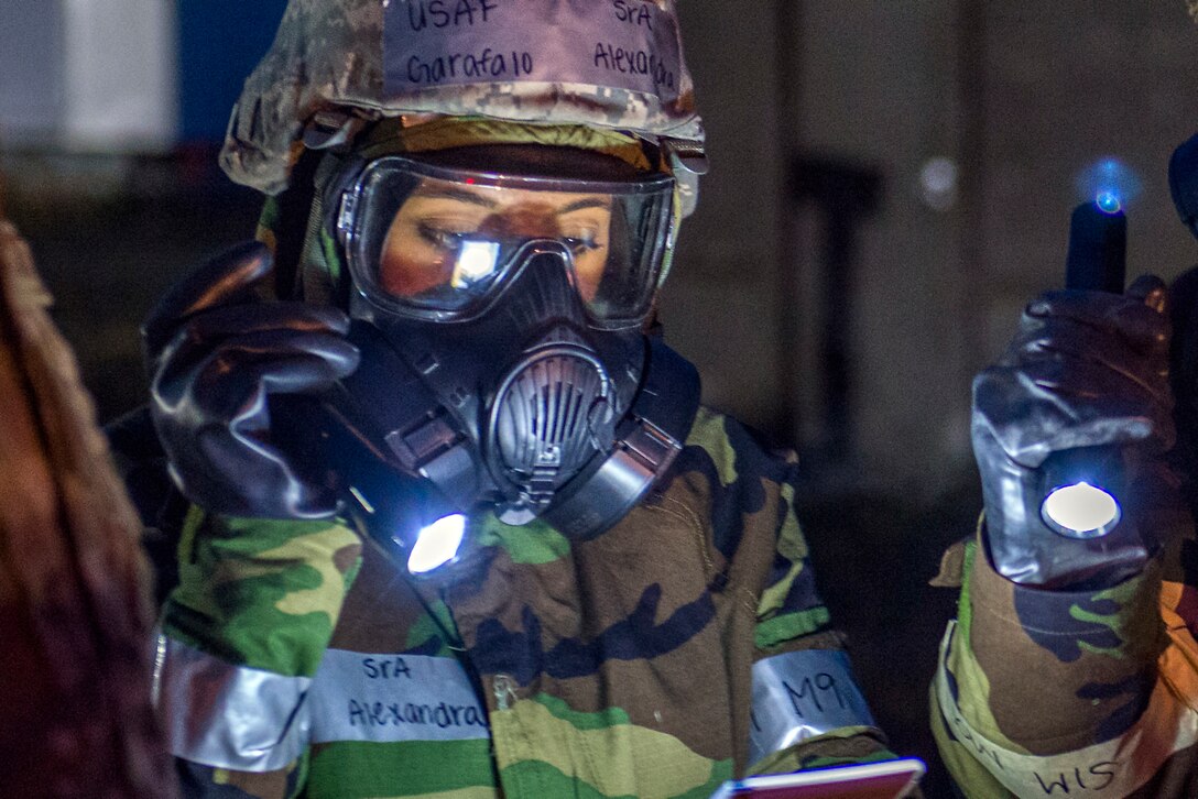 Air Airman shines a flashlight in front of her.