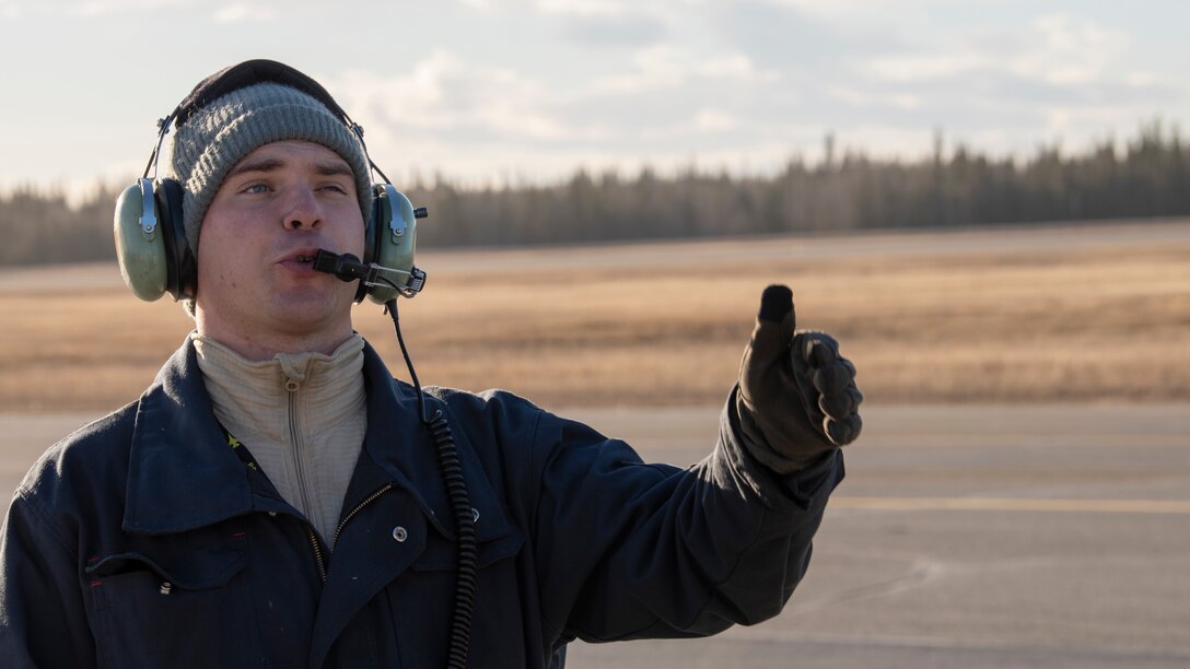 Staff Sgt. Mark Ward communicates with a fellow crew chief during exercise Distant Frontier, at Eielson Air Force Base, Alaska on October 25, 2018. Distant Frontier is a continuation of the training provided during RED FLAG-Alaska, but allows for a more tailored mission scenarios that can better meet participating unit's training objectives. (U.S. Air Force photo by Staff Sgt. Levi Rowse)