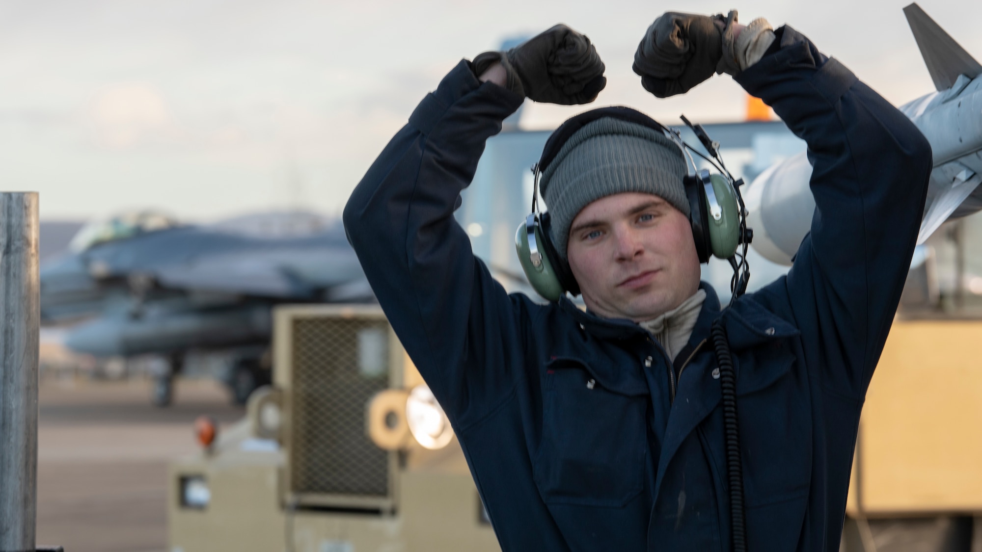 Staff Sgt. Mark Ward, a crew chief,  gives the 80th Aircraft Maintenacne Unit's "Crush'Em" sign after completing work on an F-16 Fighting Falcon during exercise Distant Frontier at Eielson Air Force Base, Alaska on October 25, 2018. Ward hails from Halls Crossroads, Tennessee and joined the Air Force in 2011. (U.S. Air Force photo by Staff Sgt. Levi Rowse)