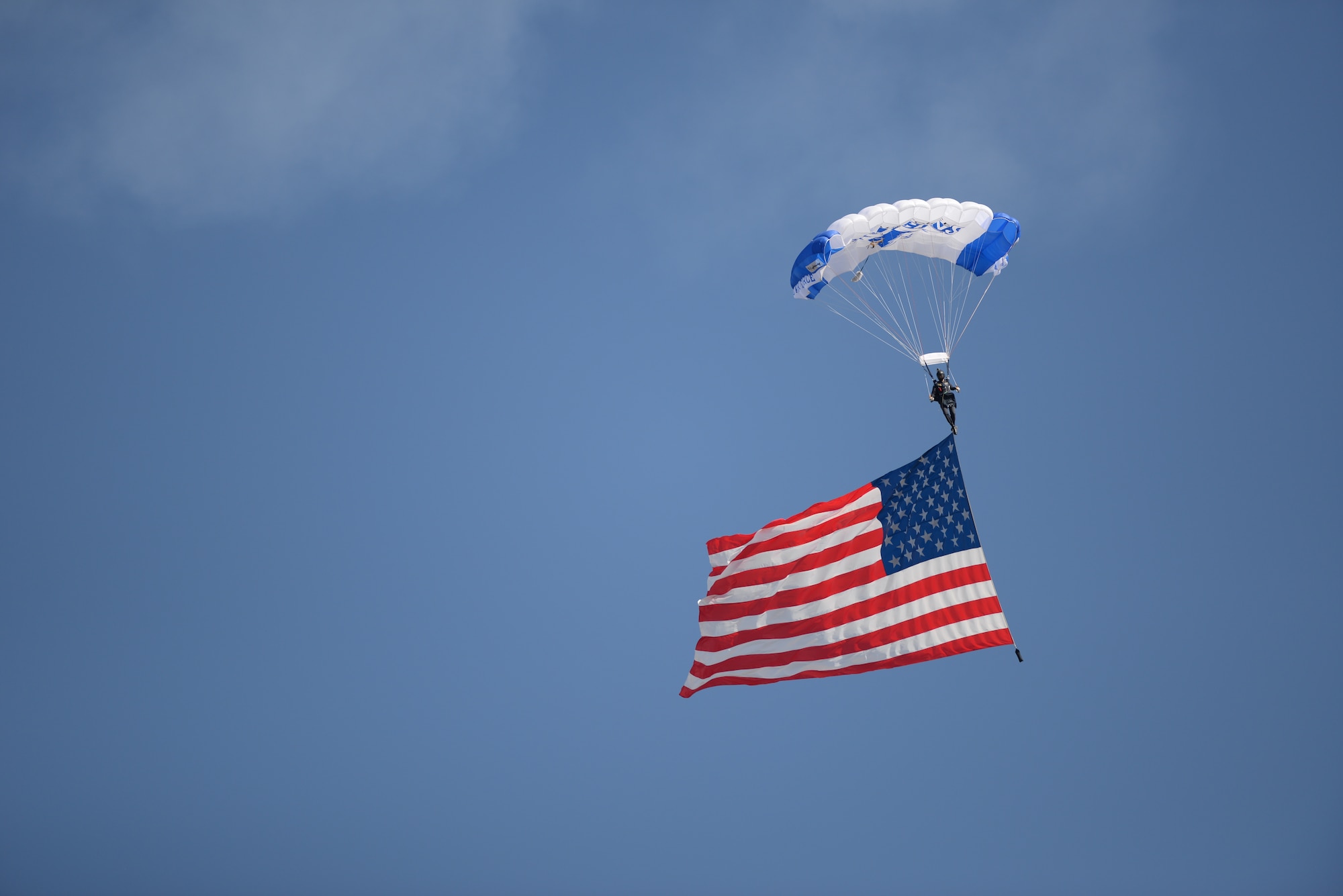 A parachutist glides down after jumping out of an aircraft holding an American flag during an air show