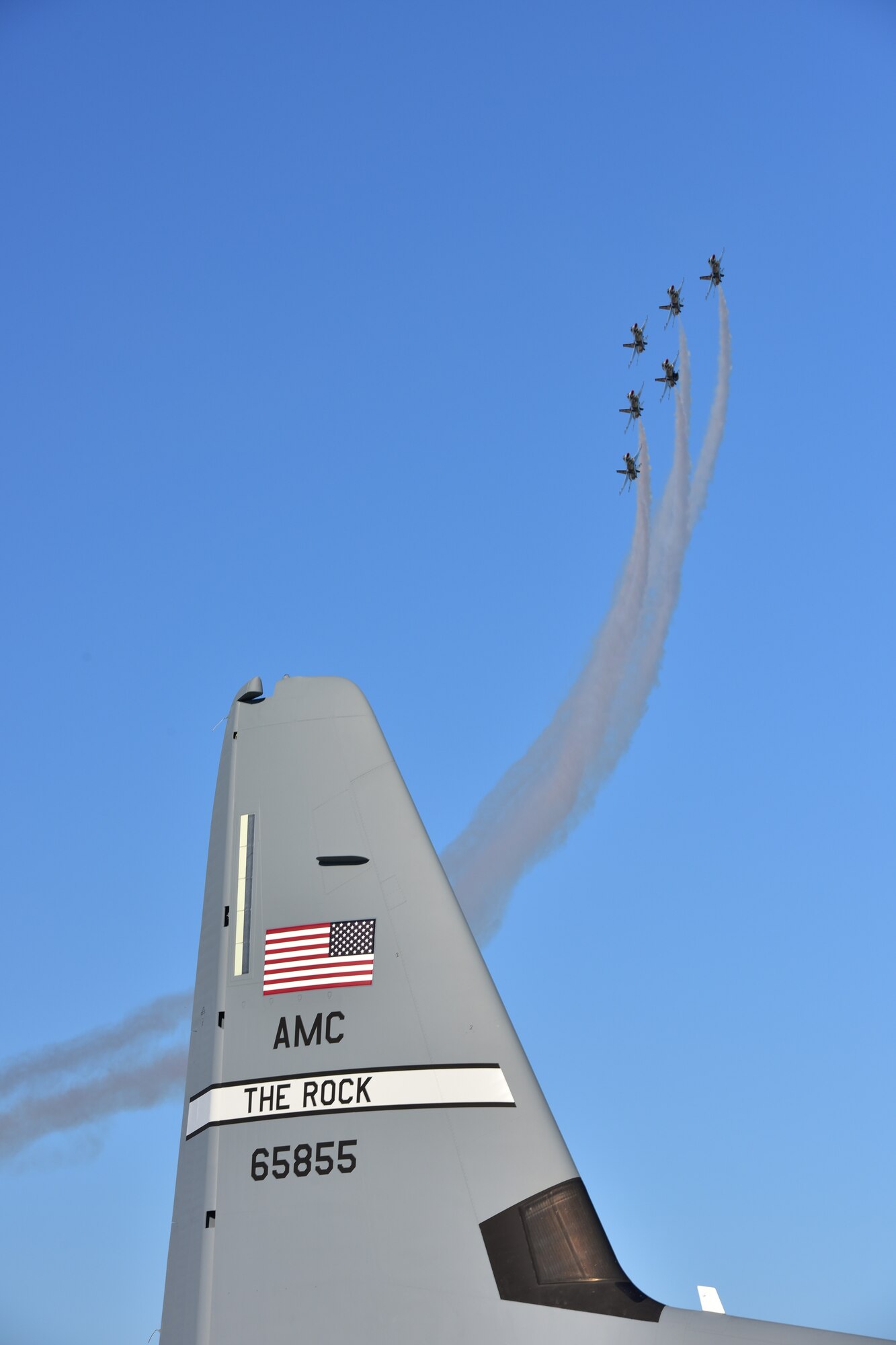 A group of U.S. Air Force Thunderbirds fly in formation around a C-130 from Little Rock