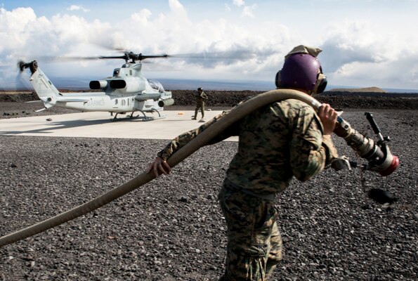 Marine Corps Cpl. Garrett Subik, a bulk fuel specialist with Marine Wing Support Detachment 24, moves a fuel line toward a landing pad in order to start fueling a AH-1W Super Cobra helicopter during a field test for an Expeditionary Mobile Fuel Additization Capability system as part of the Rim of the Pacific exercise at Pohakuloa Training Area, Hawaii.