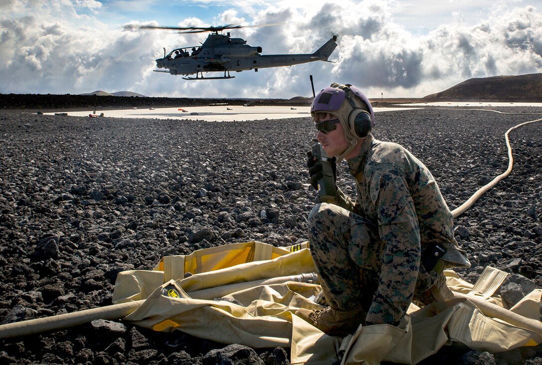 Marine Corps Cpl. Garrett Subik, a bulk fuel specialist with Marine Wing Support Detachment 24, moves a fuel line toward a landing pad in order to start fueling a AH-1W Super Cobra helicopter during a field test for an Expeditionary Mobile Fuel Additization Capability system as part of the Rim of the Pacific exercise at Pohakuloa Training Area, Hawaii.