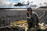 Marine Corps Cpl. Garrett Subik, a bulk fuel specialist with Marine Wing Support Detachment 24, moves a fuel line toward a landing pad in order to start fueling a AH-1W Super Cobra helicopter during a field test for an Expeditionary Mobile Fuel Additization Capability system as part of the Rim of the Pacific exercise at Pohakuloa Training Area, Hawaii.