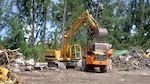 Operators use heavy equipment to load and transport millions of pounds of scrap material to heavy barges that will take it away for sorting and recycling in the city of Majuro in the Marshall Islands.