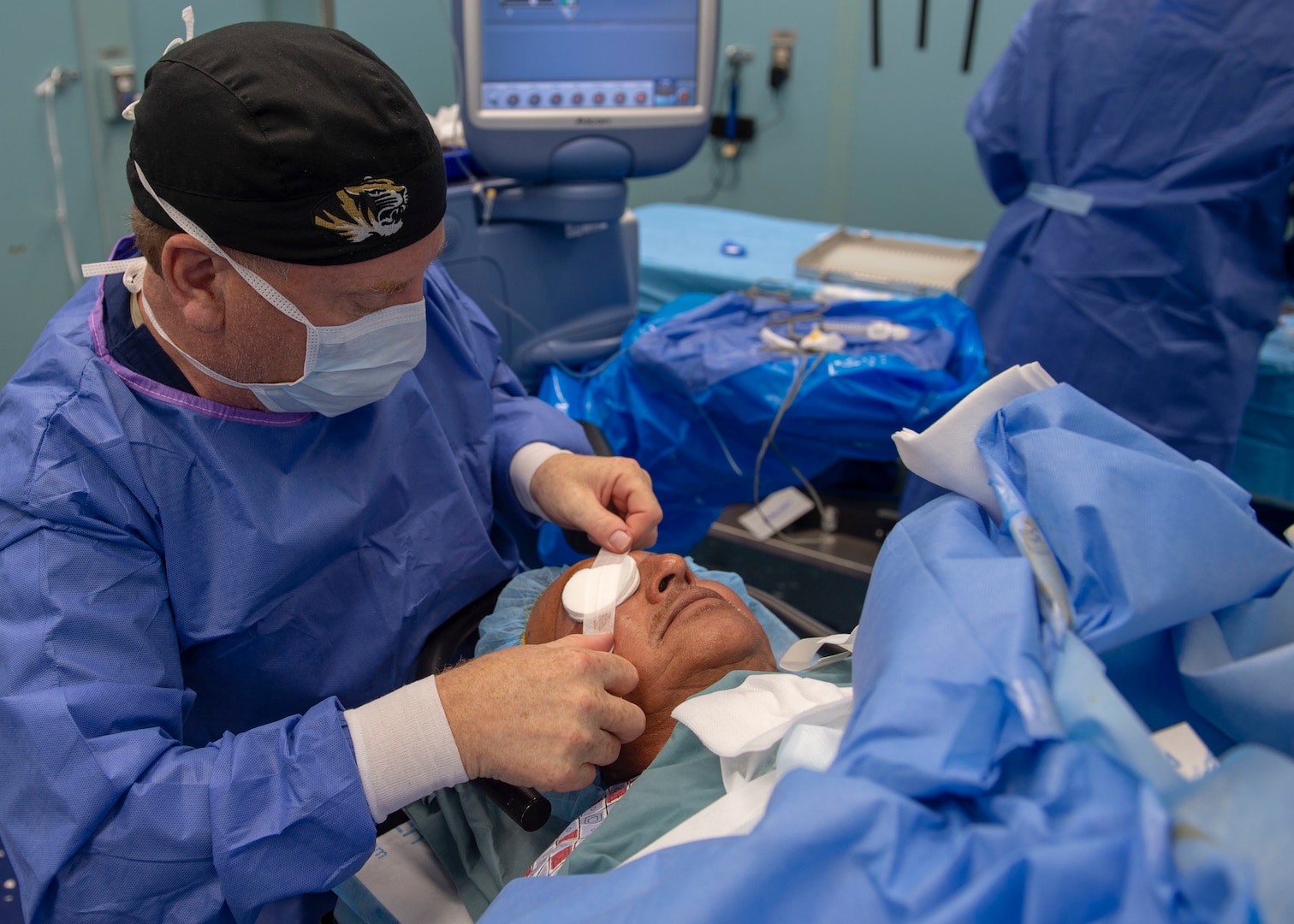 A surgeon wraps a patient’s eye after performing cataract surgery in an operating room aboard the hospital ship USNS Comfort.
