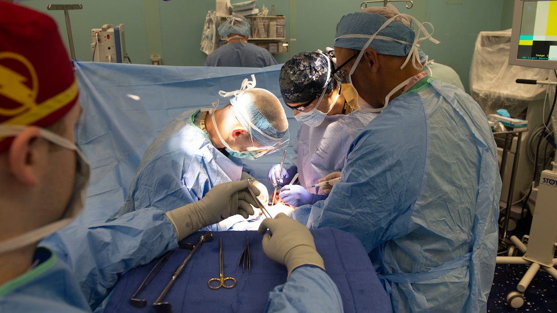 Medical personnel aboard the hospital ship USNS Comfort (T-AH 20) perform a hernia repair surgery.