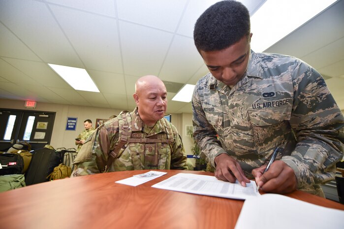 Airman 1st Class Malik Richard, 437th Aerial Port Squadron passenger operations technician, verifies a passenger’s credentials as they move through a security checkpoint as part of a mission to deploy service members through Joint Base Charleston Oct. 15, 2018.