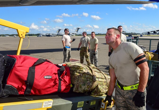 Airman 1st Class Ian Huffman, 437th Aerial Port Squadron passenger operations technician, moves baggage up a conveyer while loading luggage as part of a mission to deploy service members through Joint Base Charleston Oct. 15, 2018 in support of the Naval Station Norfolk air terminal while their airfield under goes scheduled maintenance.
