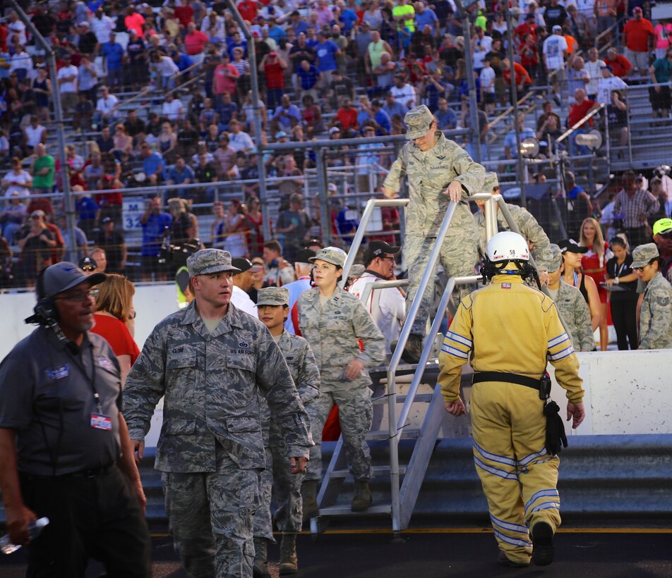 Members of the 932nd Airlift Wing and other active duty Airmen cross over the track safety barrier after helping take part in the national anthem ceremony at Gateway track.  As part of the event, 932nd Airlift Wing Maintenance Group commander, Col. Sharon Johnson, was recognized on stage with the Indy drivers at the Bommarito Automotive Group 500 Aug. 25, 2018, Gateway Motorsports Park, Madison, Illinois. Johnson was an honored VIP to help kick off the 2nd annual IndyCar race which was won by Will Power.  The 932nd Airlift Wing was represented by maintenance, medical, public affairs staff and operations personnel.  (U.S. Air Force photo by Lt. Col. Stan Paregien