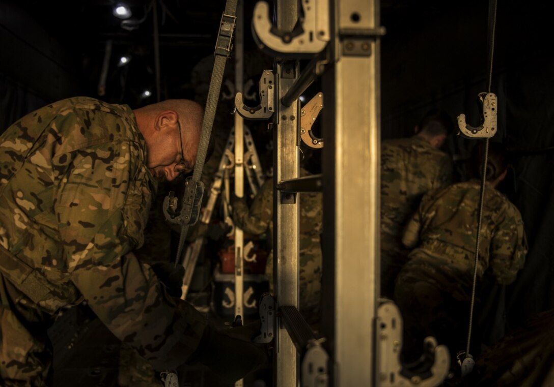 Members of the 379th Expeditionary Aeromedical Evacuation Squadron prepare to load litters onto a C-130 Hercules assigned to the 746th Expeditionary Airlift Squadron at Al Udeid Air Base, Qatar, June 15, 2018. C-130s can be configured to allow litters to be strapped to either sides of metal posts connected at the ceiling and floor of the aircraft. The aeromedical evacuation team starts by setting up the litter stanchions, then installs oxygen lines, and then attach the equipment that will be used during the mission, all before patients are brought aboard. Setting up these posts to accommodate for litter patients is time consuming, so aircrews have to work efficiently to configure the aircraft. (U.S. Air Force photo by Senior Airman Xavier Navarro)