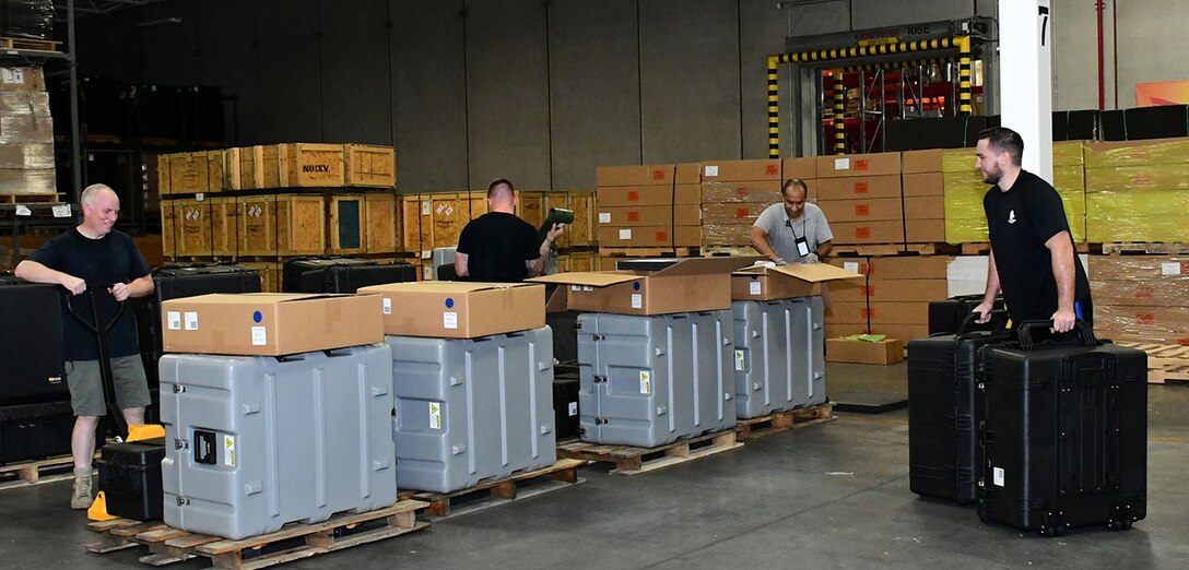 DLA Troop Support and DLA Distribution employees work together to position packing kits for vehicle-mounted speakers for shipment from DLA Distribution in New Cumberland, Pennsylvania.