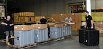 DLA Troop Support and DLA Distribution employees work together to position packing kits for vehicle-mounted speakers for shipment from DLA Distribution in New Cumberland, Pennsylvania.