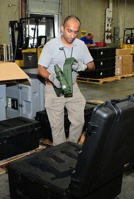 Mathew Parayll from Picatinny Arsenal, New Jersey, helps the team by inspecting a vehicle equipment mount. Moving the suspended stock takes a full complement of subject-matter experts working together.
