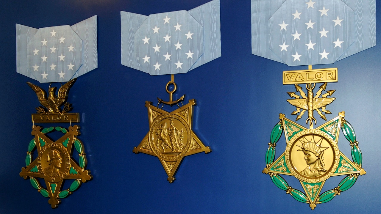 Three large recreations of Medals of Honor are displayed on a blue wall.