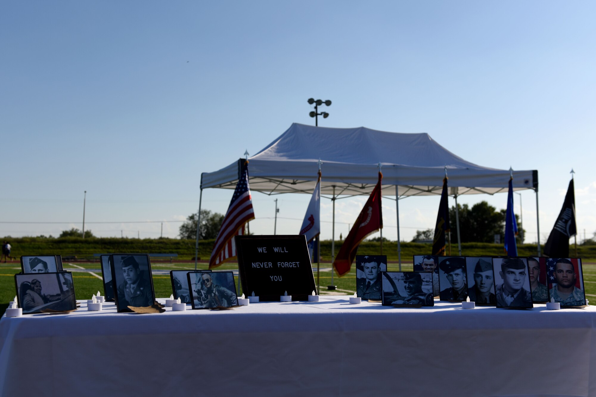 A Prisoners of War and Missing in Action memorial at the track on Goodfellow Air Force Base, Texas, Oct. 26, 2018. Photos on the table honor Texans declared as POWs or MIA.  (U.S. Air Force photo by Senior Airman Randall Moose/Released)