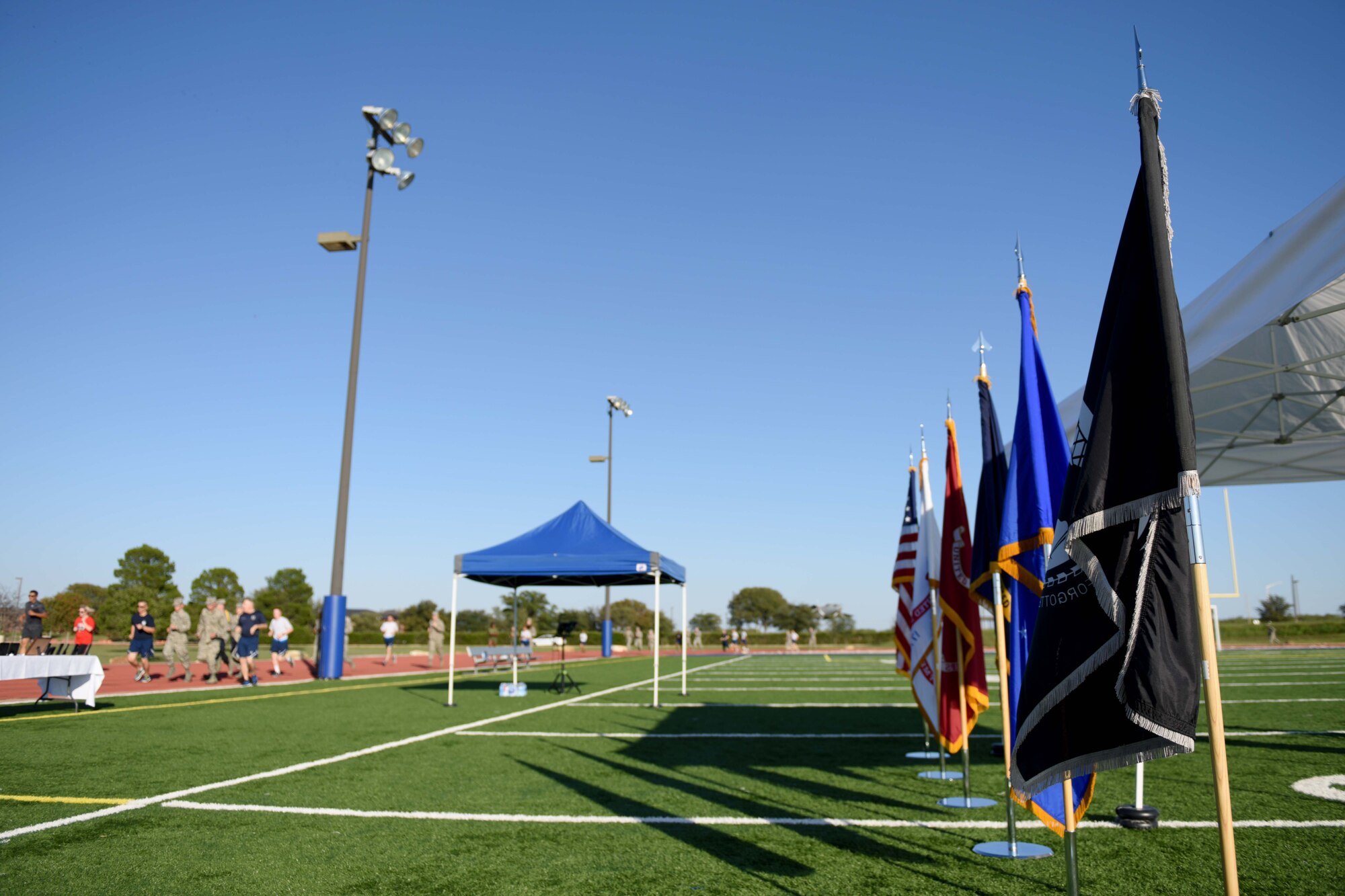 Participants run past the American flag, military service flags and a Prisoners of War and Missing in Action flag during the 24-hour Prisoners of War and Missing in Action Vigil at the track on Goodfellow Air Force Base, Texas, Oct. 26, 2018. Congress ordered prominent display of the POW/MIA flag on POW/MIA Recognition Day and several other national observances, including Armed Forces Day, Memorial Day, Flag Day, Independence Day and Veterans Day. (U.S. Air Force photo by Senior Airman Randall Moose/Released)