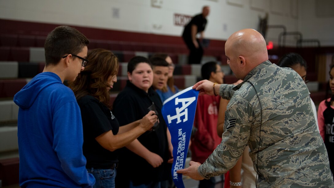 Staff Sgt. Colin Trusedell, Air Force Academy Band Blue Steel ensemble, hands students at Hoover Middle School and AFA pennant during a show at the school Oct. 25, 2018. (U.S. Air Force photo by Airman 1st Class Austin J. Prisbrey)