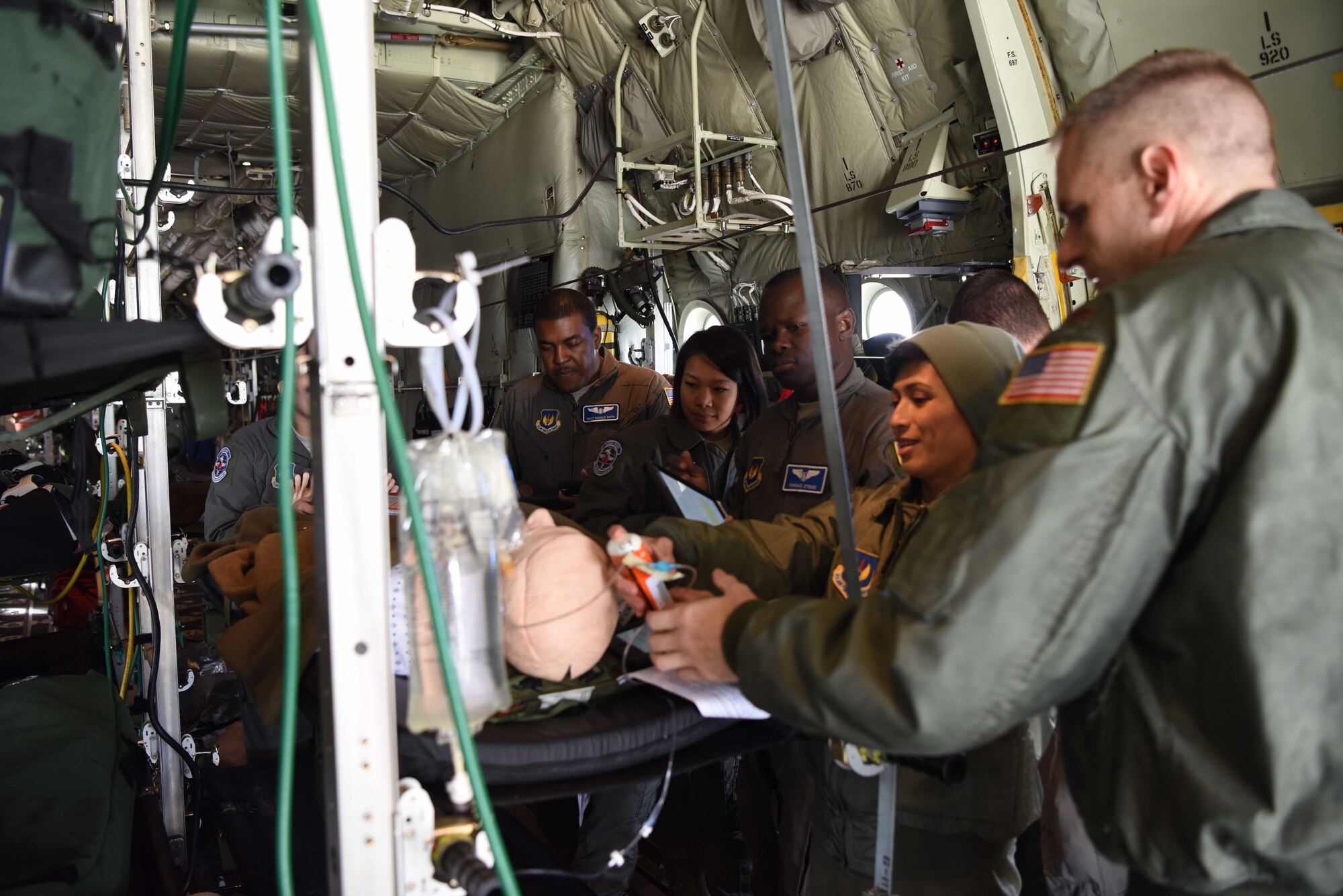 Members of the 86th Aeromedical Evacuation Squadron huddle around a medical dummy to practice clinical skills on a C-130J Super Hercules aircraft, Oct. 23, 2018. 86th AES train on an aircraft to make sure all crewmembers can fly safe, take care of patients, and are efficient in their clinical skills.