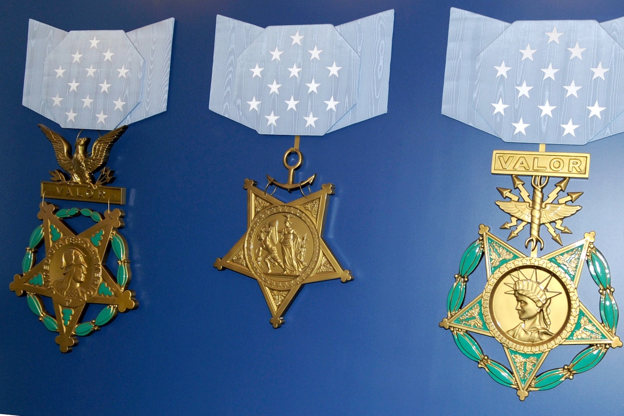 Three large recreations of Medals of Honor are displayed on a blue wall.