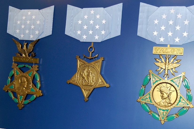 Three large recreations of Medals of Honor are displayed on a blue wall.