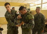 Canadian Forces Master Corporal Kristian Tam, discusses field medicine techniques during a multi-nation information exchange meeting on medicine in a tactical environment with American and Ecuadorian service members.