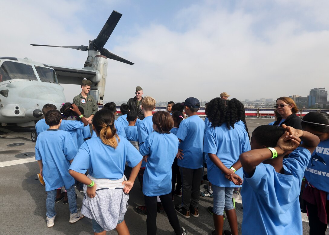 U.S. Marines Cpt. Daniel Hopkins, a MV-22 Osprey pilot, and Cpl. James Snow, a crew chief with Marine Medium Tilt Rotor Squadron (VMM) 161, Marine Aircraft Group (MAG) 16, 3rd Marine Air Wing (MAW), teach student about their aircraft during students day Fleet Week San Diego 2018, San Diego, California, Oct. 25. Fleet Week San Diego 2018 gives service members the opportunity to show community involvement, develop stronger relationships with other branches and highlight the positive military presence in the heart of San Diego.(U.S. Marine Corps photograph by Cpl. Joshua S. McAlpine)