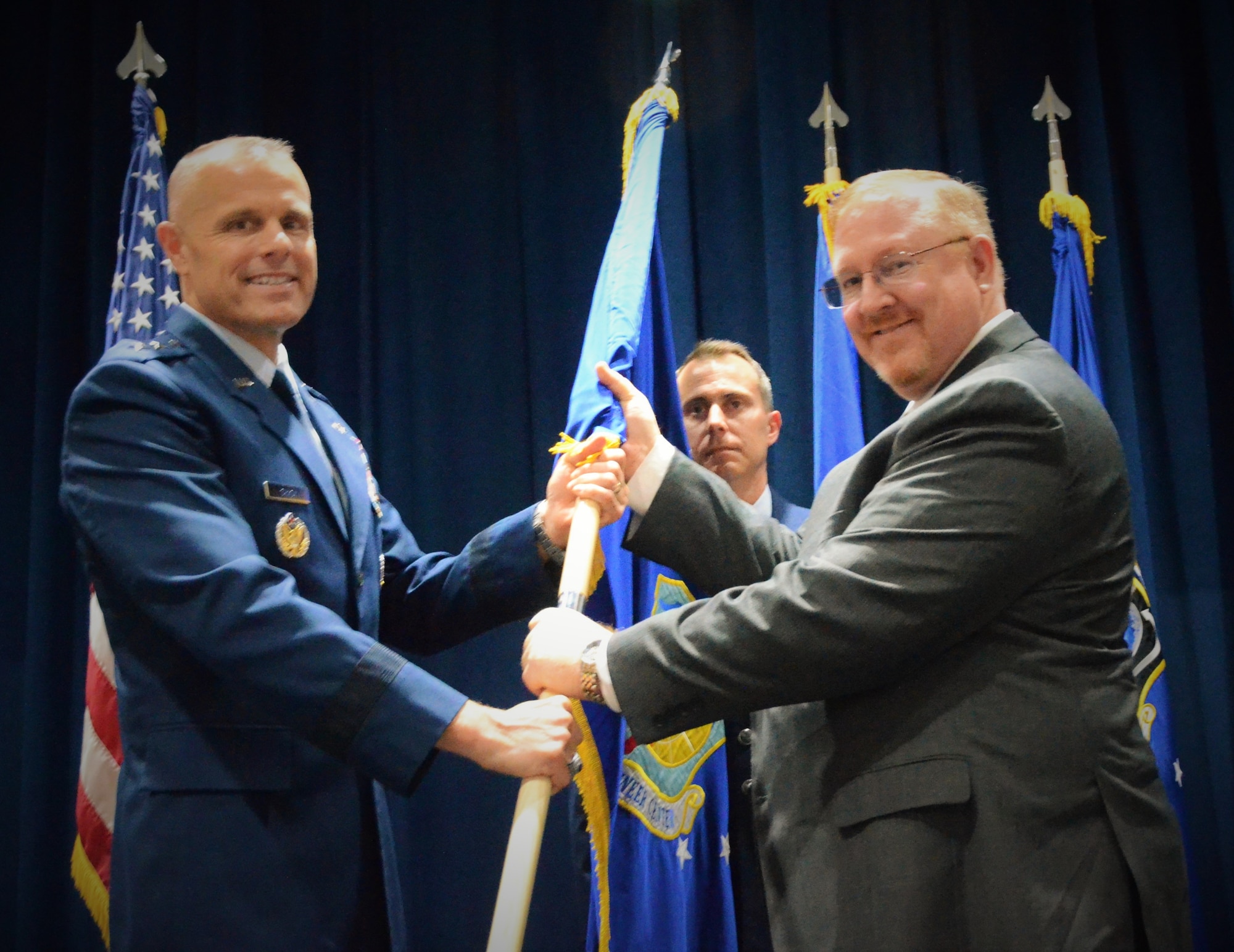 Terry Edwards accepts the Air Force Civil Engineer Center flag from Maj. Gen. Bradley D. Spacy, Commander, Air Force Installation and Mission Support Center during a change of leadership ceremony at Lackland Air Force Base, Texas, Oct. 29, 2018.