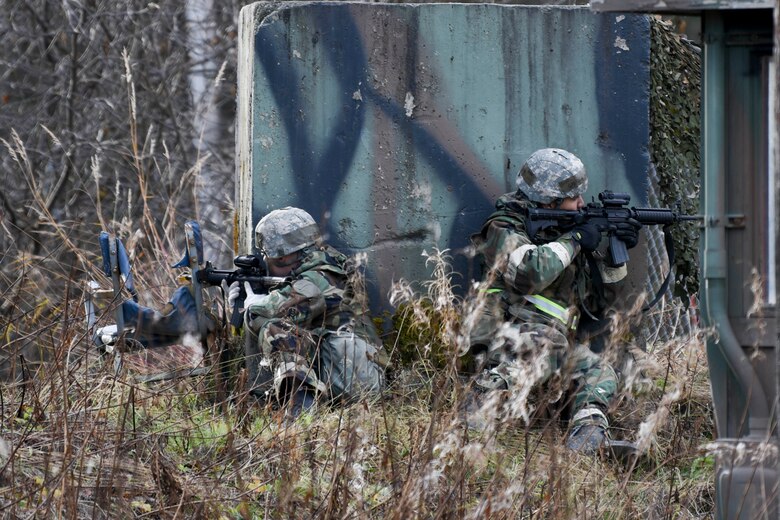 U.S. Air Force Airman Nicholas Simonin and Airman Gabriel Montoya Lopez, both from the 773d Civil Engineer Squadron, hold their M4 carbines while acting as extra entry control center security during a mock attack during exercise Polar Force 19-1 at Joint Base Elmendorf-Richardson, Alaska, Oct. 25, 2018. Exercise Polar Force showcases unit combat readiness while fighting in chemical, biological, radiological and nuclear defense protective gear.