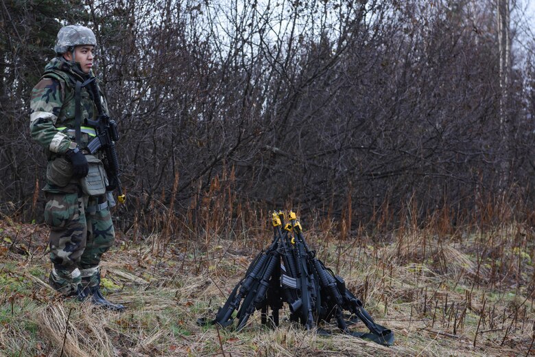 U.S. Air Force Airman Gabriel Montoya Lopez, 773d Civil Engineer Squadron, watches over a cluster of M4 carbines used during exercise Polar Force 19-1 at Joint Base Elmendorf-Richardson, Alaska, Oct. 25, 2018. Exercise Polar Force showcases unit combat readiness while fighting in chemical, biological, radiological and nuclear defense protective gear.