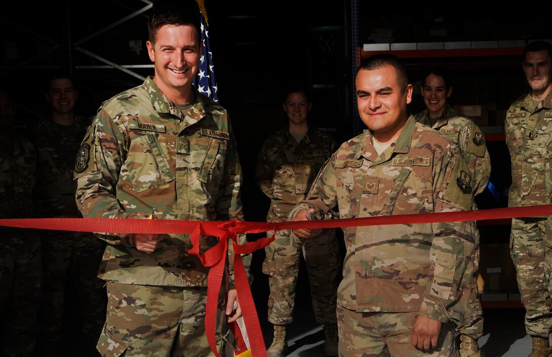 Airman 1st Class Dustin Marin, left, 379th Expeditionary Logistics Readiness Squadron materiel management technician, and Staff Sgt. Mario Lopez, right, 379th ELRS materiel management craftsman, cut a ribbon during the opening of the new Desert Depot Oct. 30, 2018, at Al Udeid Air Base, Qatar. The ceremony completes a two-year effort to relocate to a $1.1 million facility. Airmen of the 379th ELRS pulled together to move 42,000 assets to the new location during a four-day period. (U.S. Air Force photo by Tech. Sgt. Christopher Hubenthal)