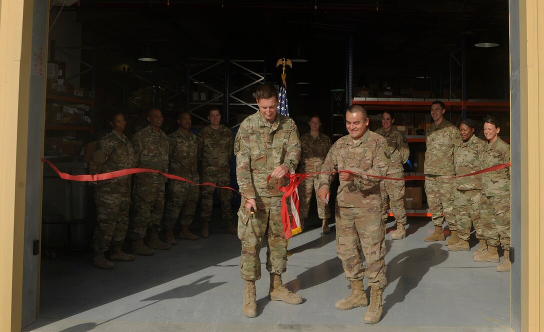 Airman 1st Class Dustin Marin, left, 379th Expeditionary Logistics Readiness Squadron materiel management technician, and Staff Sgt. Mario Lopez, right, 379th ELRS materiel management craftsman, cut a ribbon during the grand opening of the new Desert Depot Oct. 30, 2018, at Al Udeid Air Base, Qatar. The ceremony completes a two-year effort to relocate to a $1.1 million facility. Airmen of the 379th ELRS pulled together to move 42,000 assets to the new location during a four-day period. (U.S. Air Force photo by Tech. Sgt. Christopher Hubenthal)