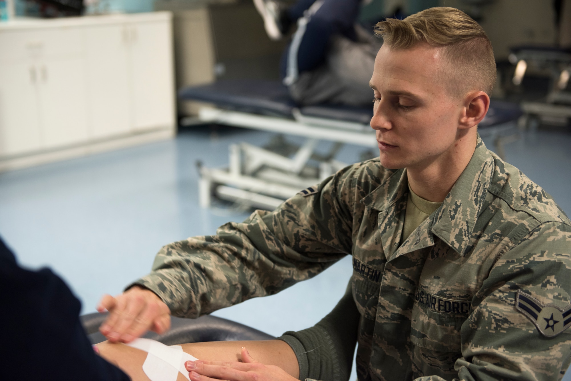 Airman 1st Class Heath Martin, 48th Medical Operations Squadron physical medicine technician, applies a bandage to a patient in the Physical Therapy Clinic at Royal Air Force Lakenheath, England, Oct. 30. The Physical Therapy Clinic provides therapeutic exercises, post-operation rehabilitation, dry needling and other services to patients. (U.S. Air Force photo/ Senior Airman Malcolm Mayfield)