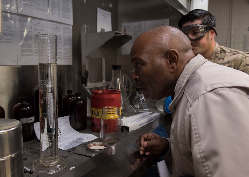 James Ruffin, Academy of Hampton science teacher, and U.S. Air Force Staff Sgt. John Pisano, 733rd Logistics Readiness Squadron fuels lab non-commissioned officer in charge, observe a fuel test at Joint Base Langley-Eustis, Virginia, Oct. 25, 2018.