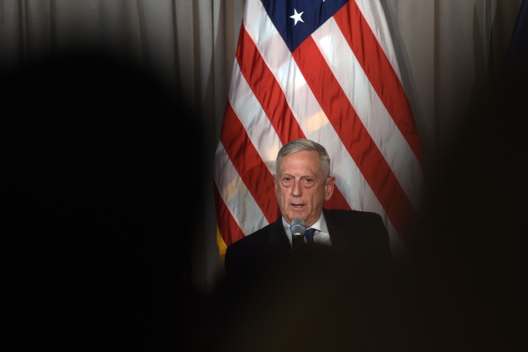 Defense Secretary James N. Mattis speaks with a U.S. flag as his backdrop.