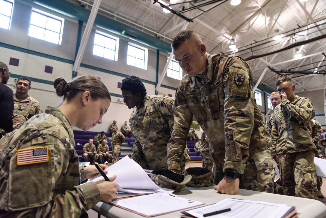 U.S. Army Sgt. Hannah O’Henry and Sgt. Joshua Garcia, 331st Transportation Company, 11th Transportation Battalion, 7th Transportation Brigade (Expeditionary), review Garcia’s deployment paperwork to confirm his readiness at Joint Base Langley-Eustis, Virginia, Oct. 22, 2018.