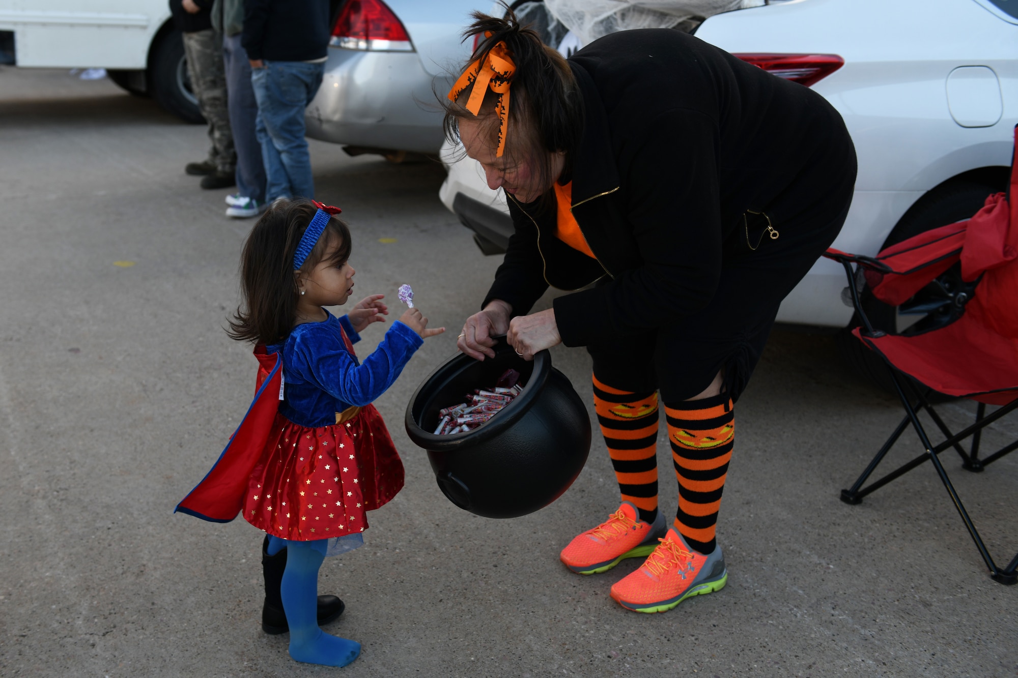Sabrina Rodriguez, the daughter of Senior Airman Manuel Rodriguez-Sepulveda, a 28th Aircraft Maintenance Squadron hydraulics technician, collects candy from Angela Gadomski, a retired youth center sports director, at the Pride Hangar parking lot on Ellsworth Air Force Base, S.D., Oct. 26, 2018. The Trunk or Treat event promotes morale for service members and their families. (U.S. Air Force photo by Airman 1st Class Christina Bennett)
