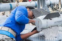 U.S. Air Force Staff Sgt. Kayla Fitzgerald, a 525th Aircraft Maintenance Unit weapons load crew team chief, attaches stabilization fins to an AIM-120 Advanced Medium Range Air-to-Air Missile during the quarterly load competition at Joint Base Elmendorf-Richardson, Alaska, Oct. 26, 2018. The AIM-120 is a medium range missile used for air intercept and has an approximate weight of 358 lbs.