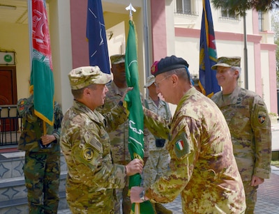 An Italian Army general passes the Resolute Support Mission flag to U.S. Army Gen. Austin S. Miller.
